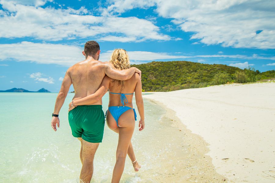 a couple walking along the sand on whitehaven beach
