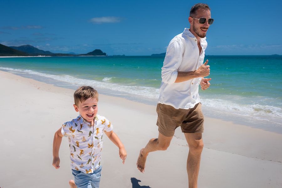A father and young son running along the beach
