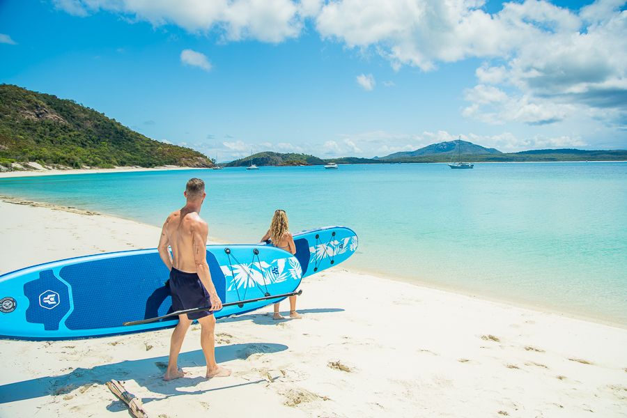 Paddleboards Whitehaven Beach people with paddleboards walking on whitehaven beach