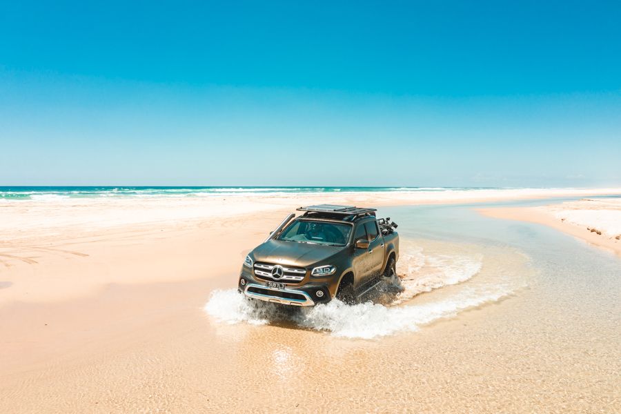 4WD truck driving through sand and water on K'gari