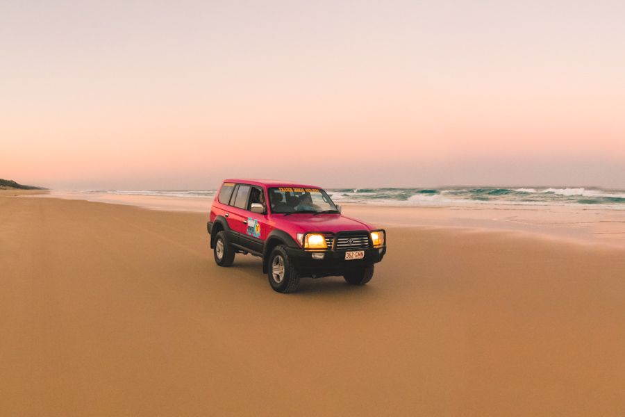 pink 4wd on the beach on k'gari at dusk