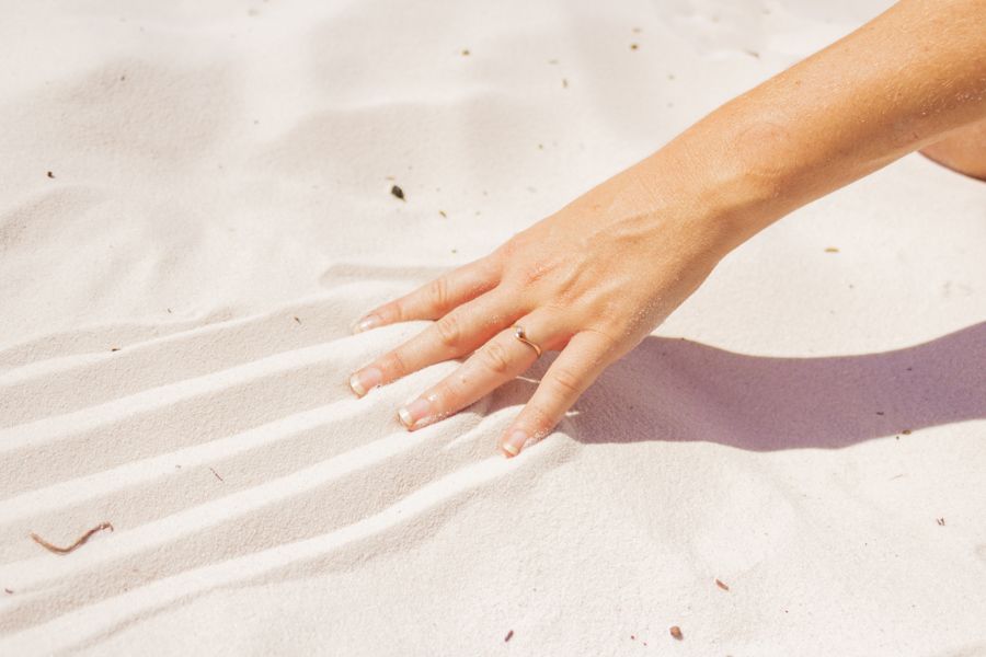 person running hands over the soft white sand at lake mckenzie