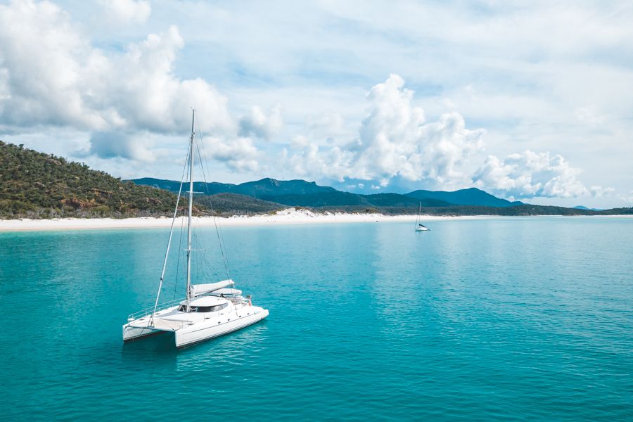 catamaran cruising on turquoise water next to Whitehaven Beach