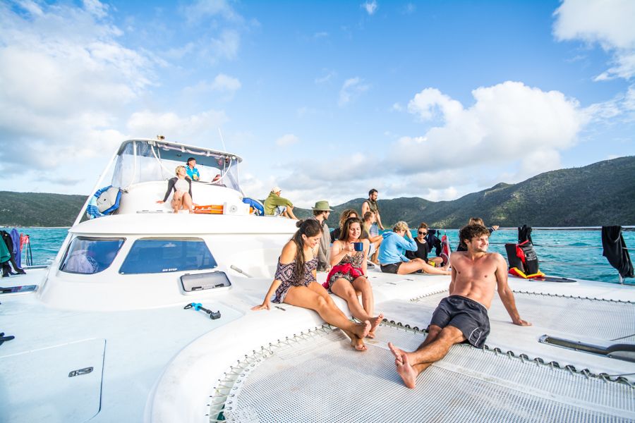 A group of people sitting on the top of a yacht in blue water