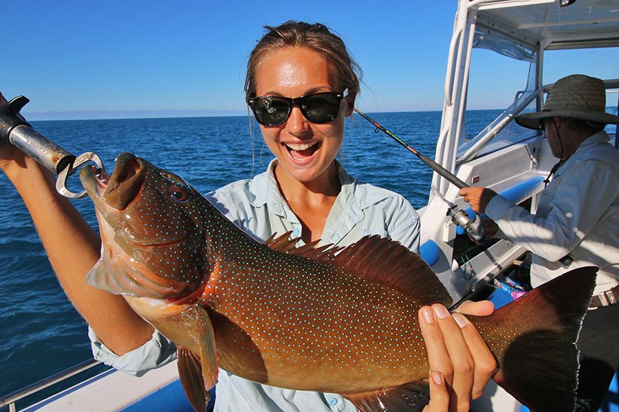 girl holding a fish while on a boat at sea