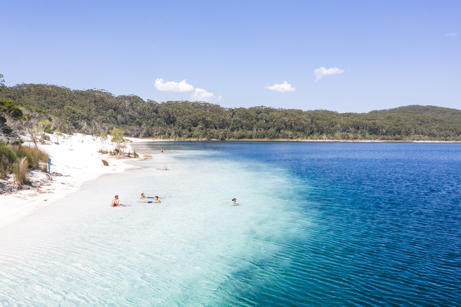 three people floating in Lake McKenzie's blue water