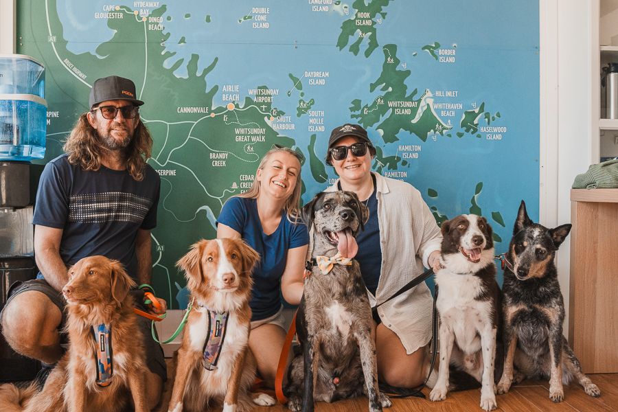 A group of adults with different dogs outside The Travel Shop, Airlie Beach