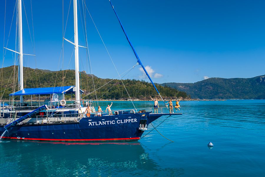 a group of people standing at the bow of a sail boat