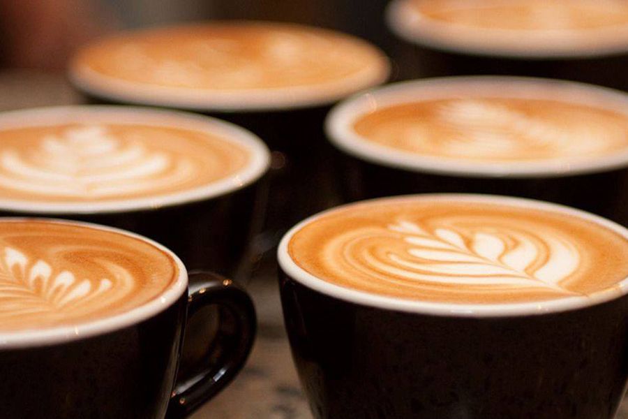 Coffees with latte art on top in wide navy mugs