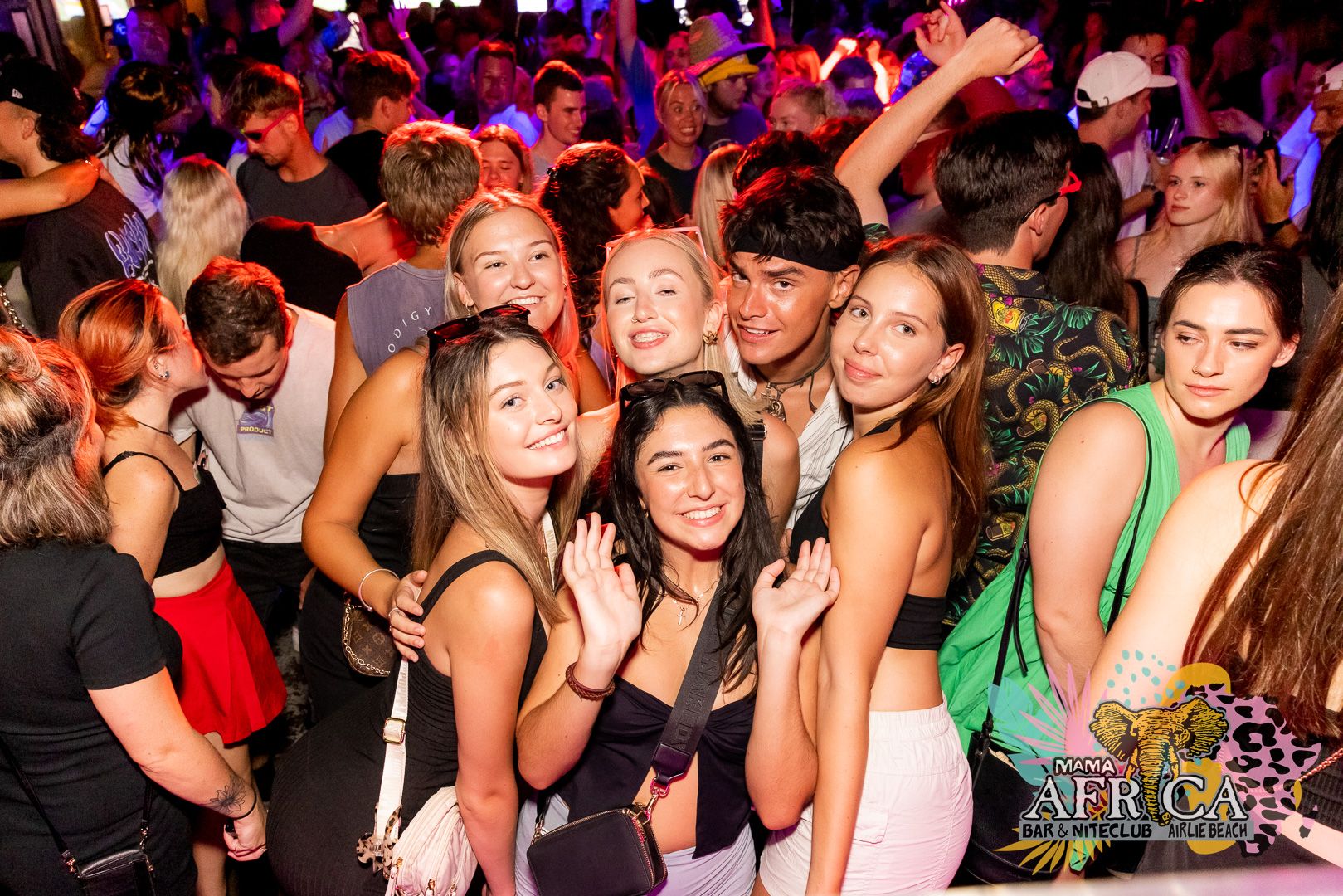 A group of young people smiling in a photo on a nightclub dance floor