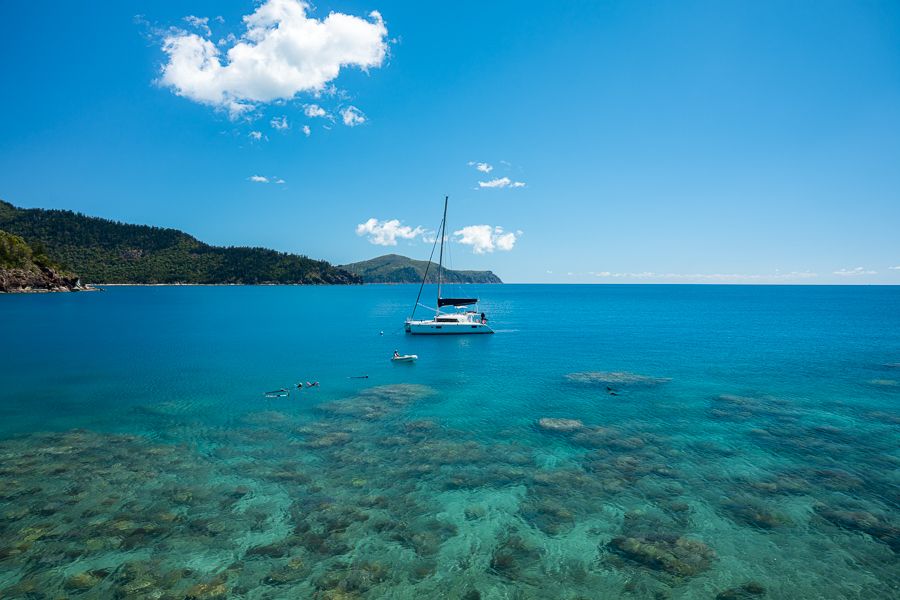 whitsunday catamaran next to coral reefs and islands
