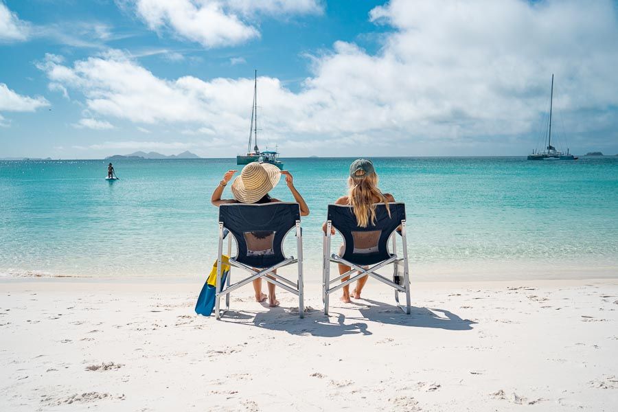 Two people in camping chairs looking out at Whitehaven Beach