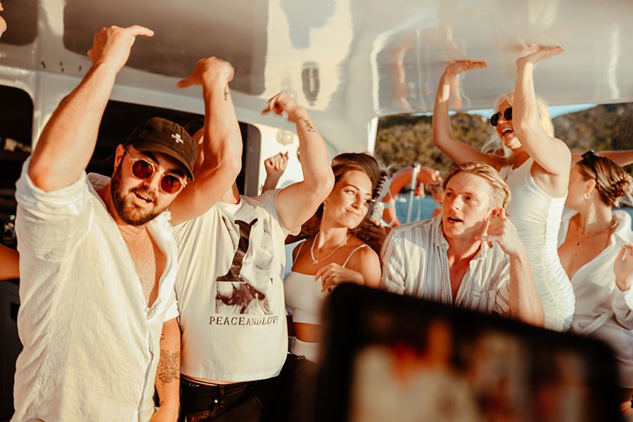 People in white dancing on a white boat in the islands