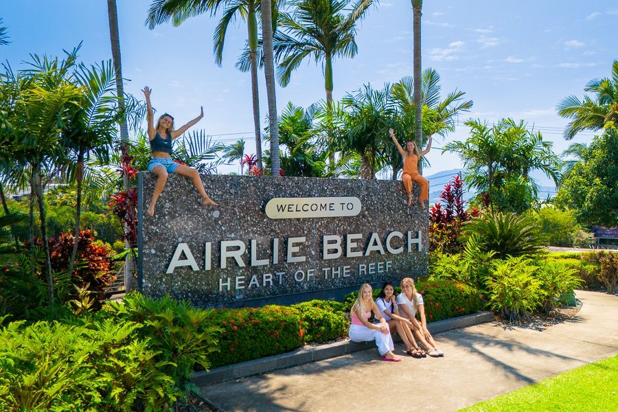 people posing in front of whitsundays airlie beach sign