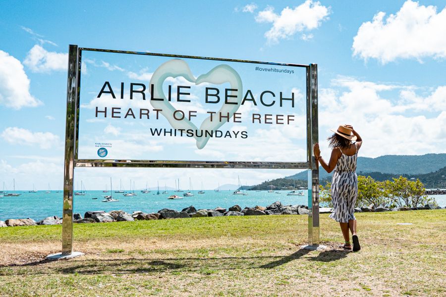 Women standing in front of Airlie Beach town sign