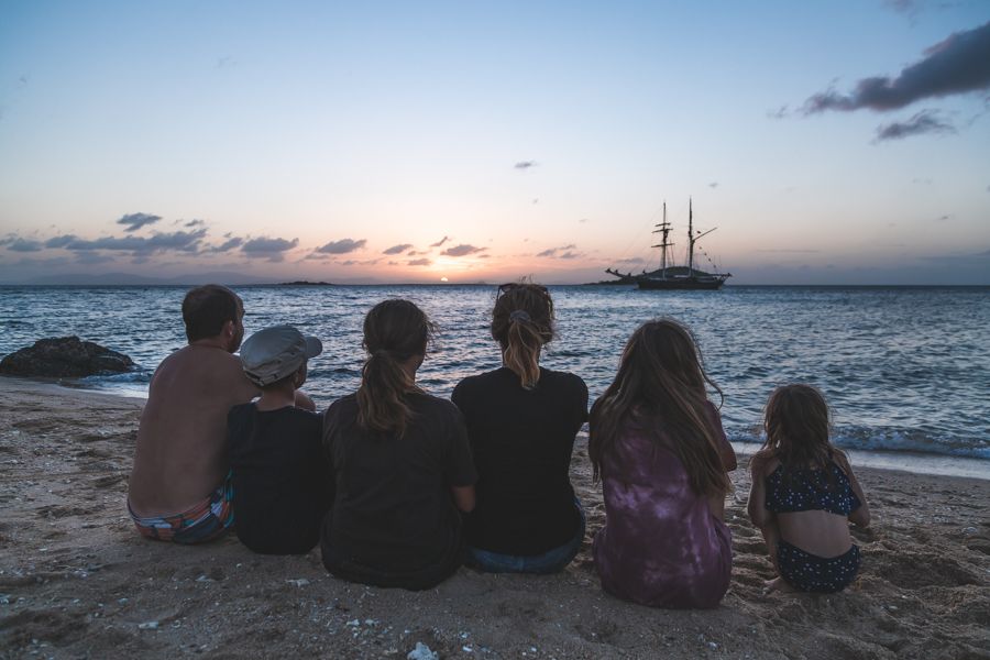 Family sitting on Airlie Beach look at the sunset over the Whitsundays