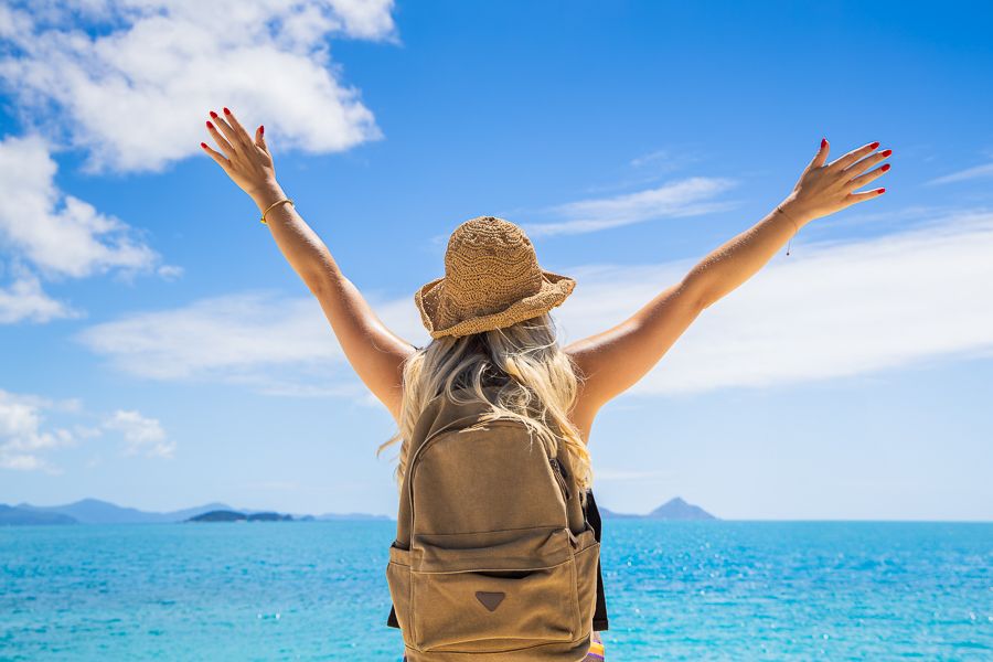 a woman wearing a backpack with her arms in the air