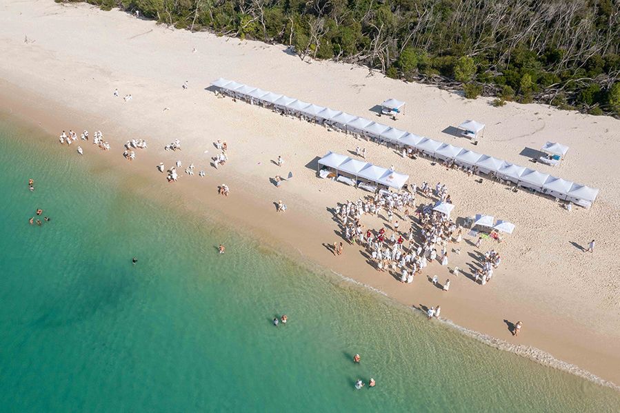 People gathered under stretching white marquees on Whitehaven Beach for White on Whitehaven Long Lunch by Fish D’vine 2021