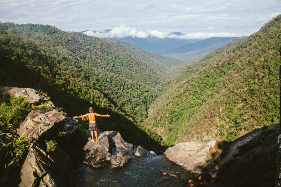 Cairns man with arms outstretched, overlooking green mountains 