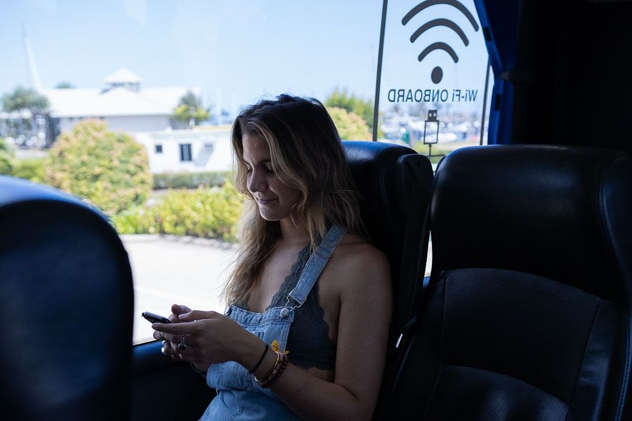 Person checking their phone whilst travelling on a Greyhound Bus to Airlie Beach.