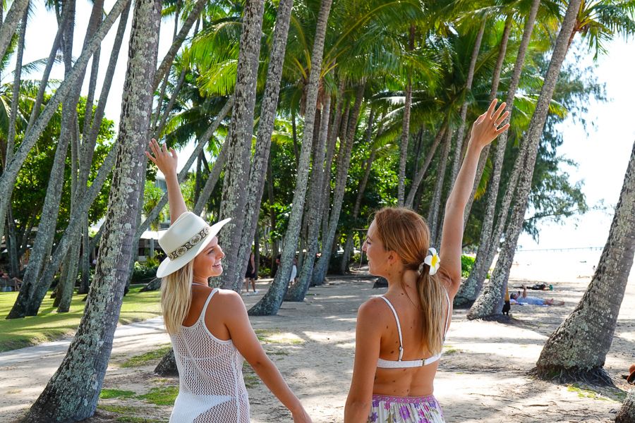 Two girls walking through a row of palm trees