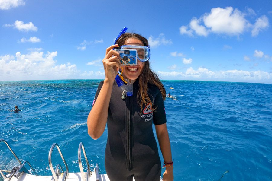 Women in a wetsuit holding up an underwater camera