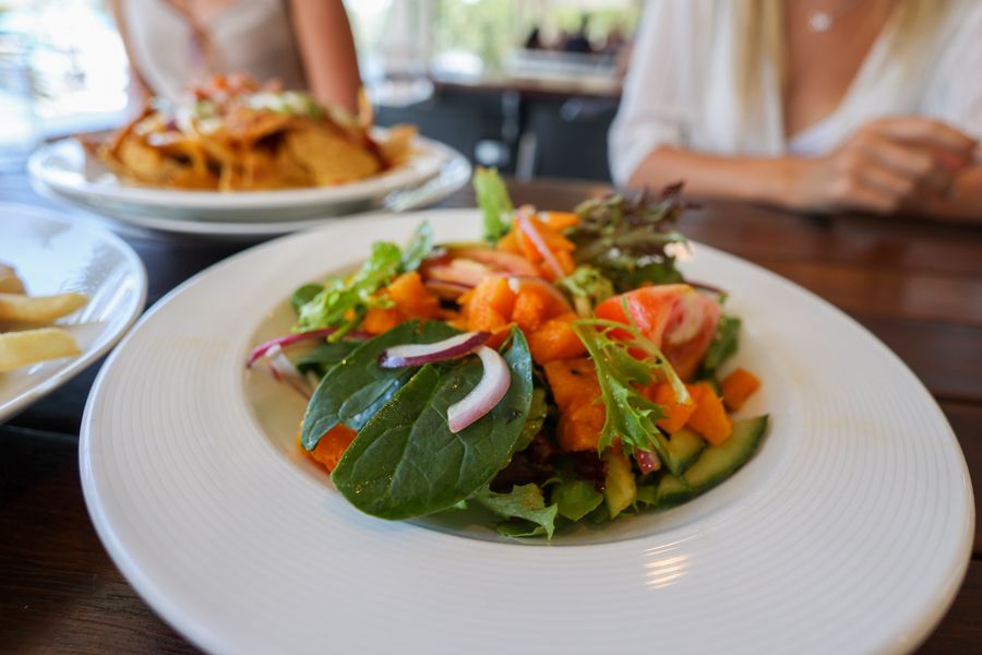 nachos, salads and chips on a colourful table with friends eating