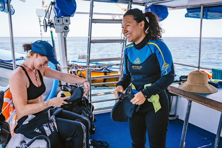 Two people putting on stinger suits on a dive boat on the Great Barrier Reef