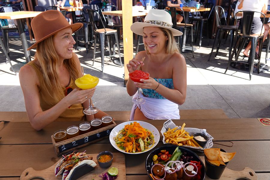 Two girls in a hat with cocktails and food