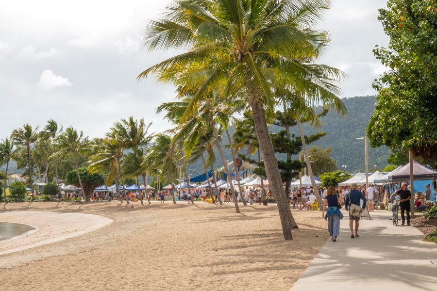 White market stalls lined up along the beach with palm trees around