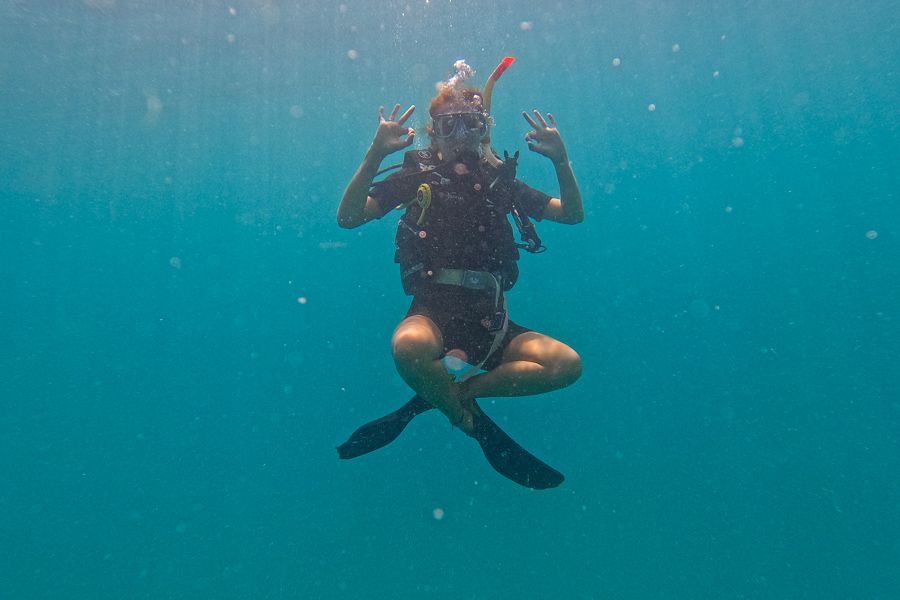 Person scuba diving in the ocean with legs crossed