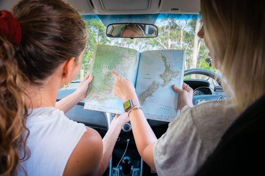 Australia road trip Two girls looking at a map while on a road trip