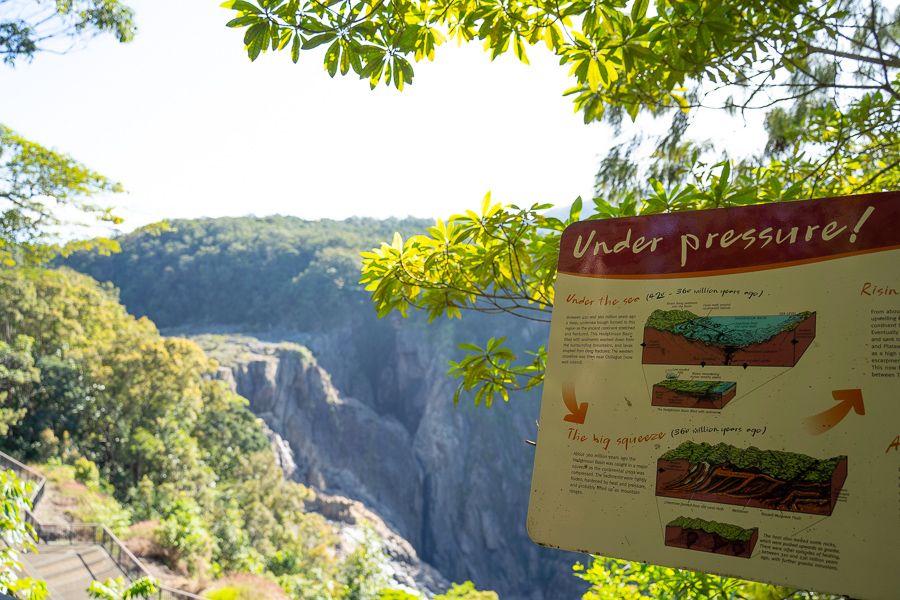 Viewing platform and national park information signs in foreground, Barron Falls rainforest in background