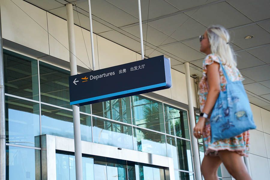 A woman looking up at a departure sign outside an airport