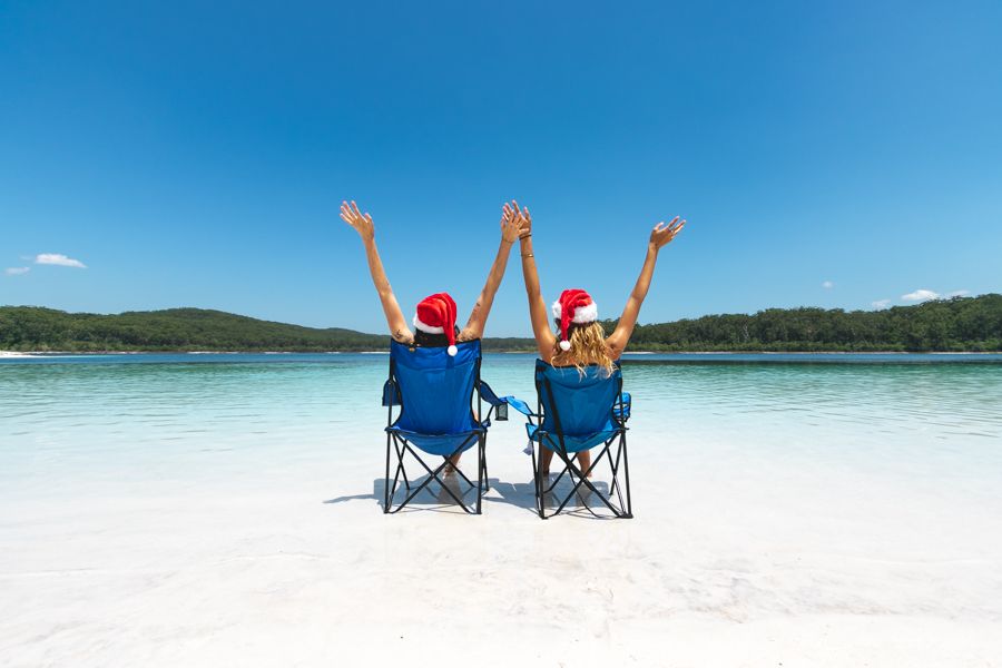 two girls in santa hats sittin gin camping chairs