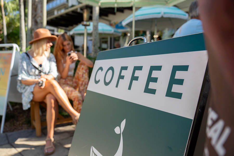 Two women waiting for coffee, coffee sign in front of Cafe