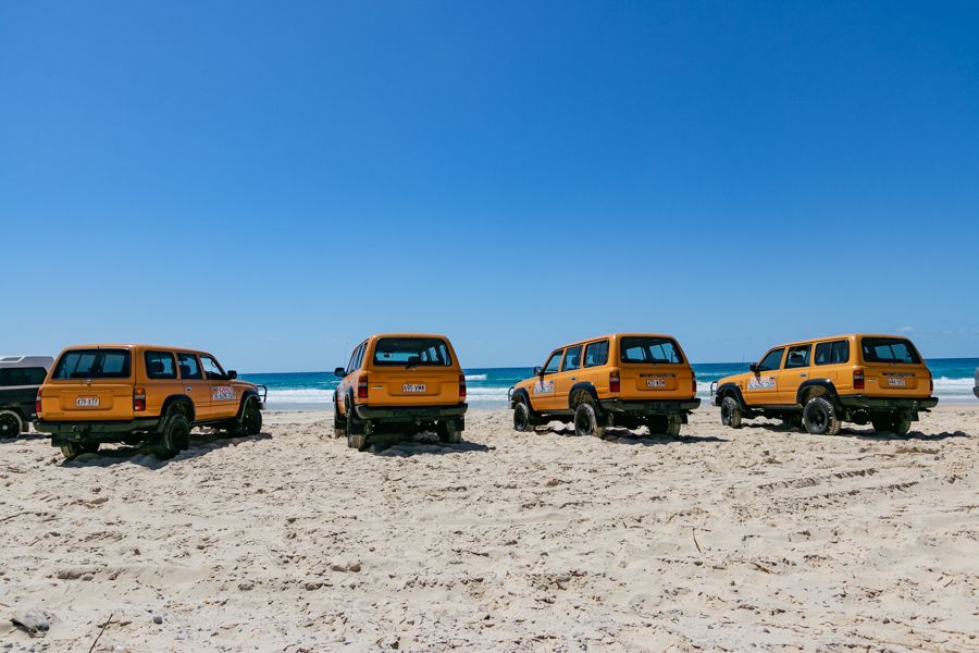 yellow 4WD vehicles parked near the beach