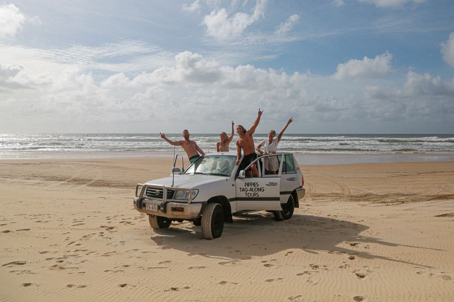 group of people in a truck on the beach on fraser island