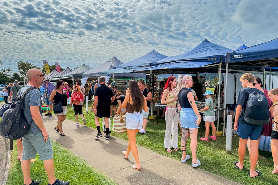 people walking around the stalls at airlie beach markets