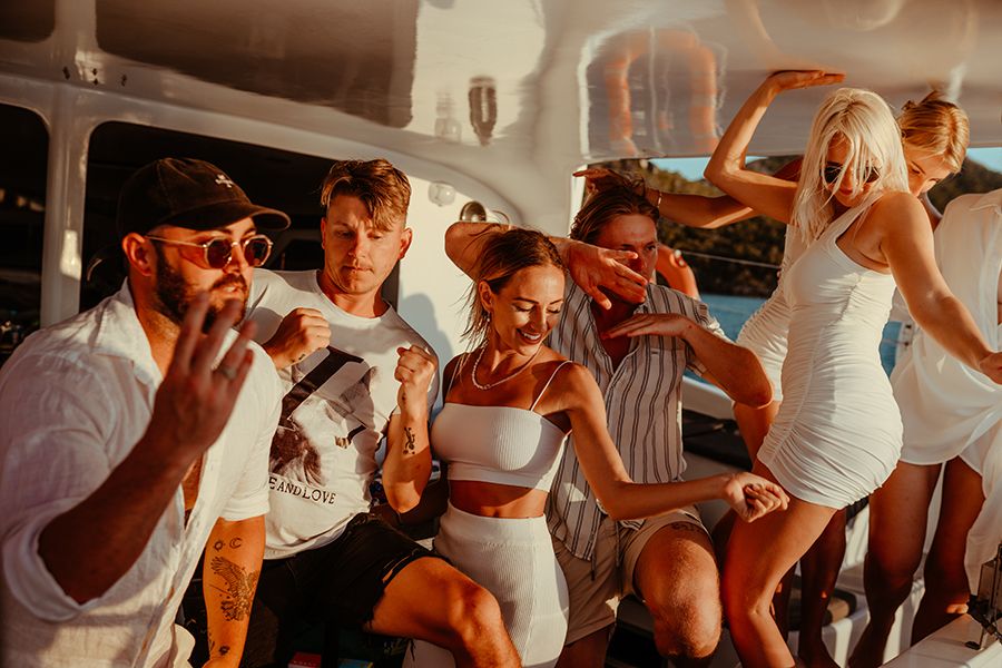 Group of young people in white dancing on Powerplay catamaran