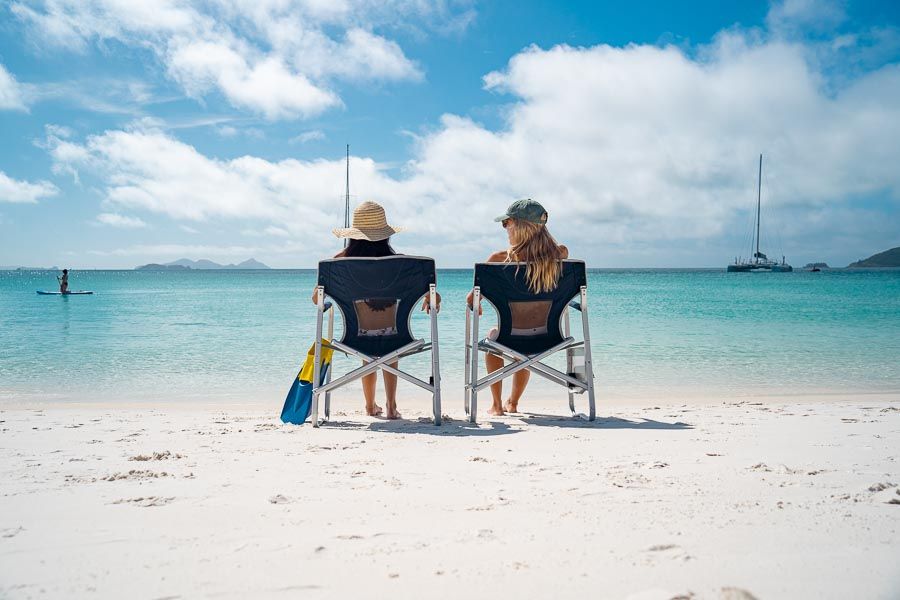 two people sitting in beach chairs on the beach