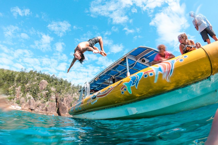 person filpping off a boat into the water in the Whitsundays