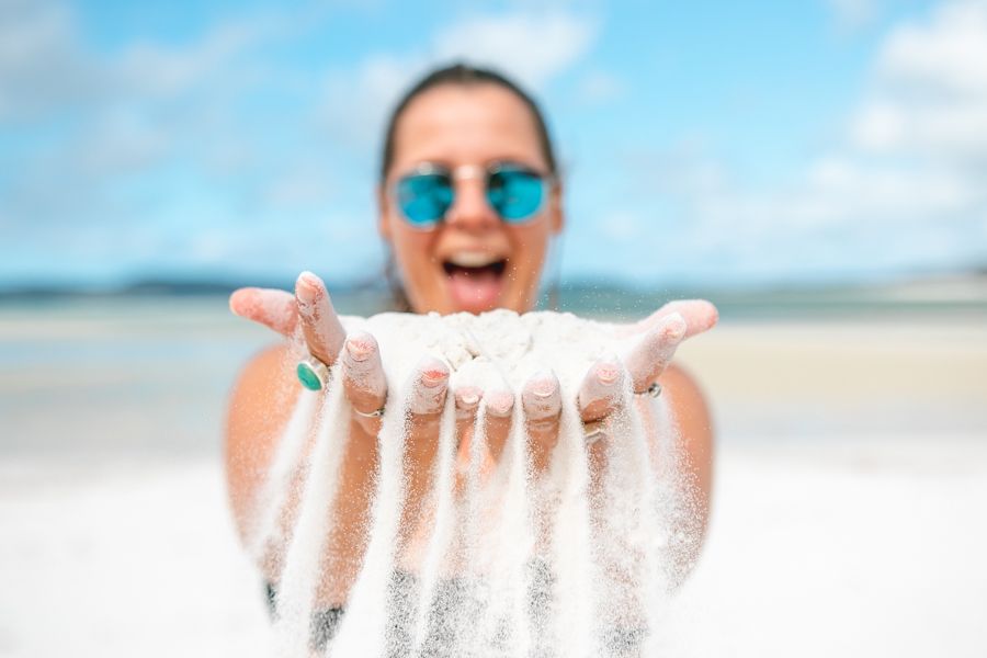 person holing up soft white sand on Whitehaven Beach