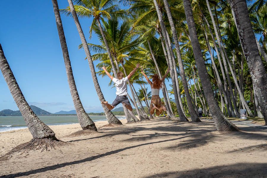 Two people jumping between palm trees in palm cove