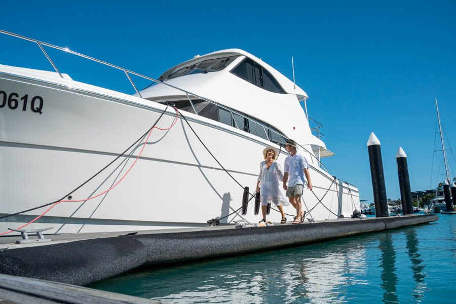 Two people strolling past a luxury yacht in the Hamilton Island Marina