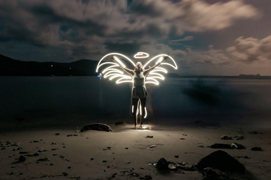 Person silhouetted with light up angel wings