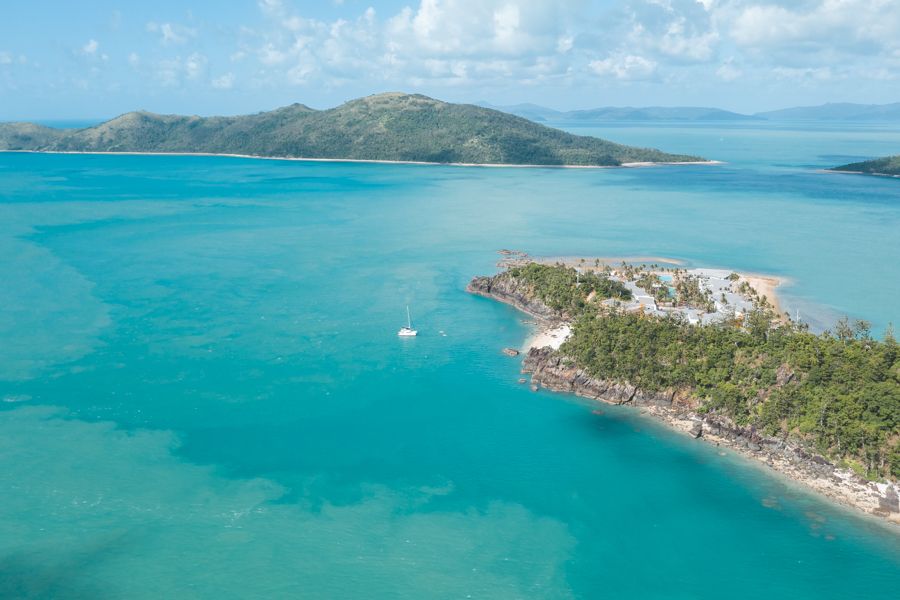 Longshot aerial of catamaran anchored in Whitsunday waters between two islands