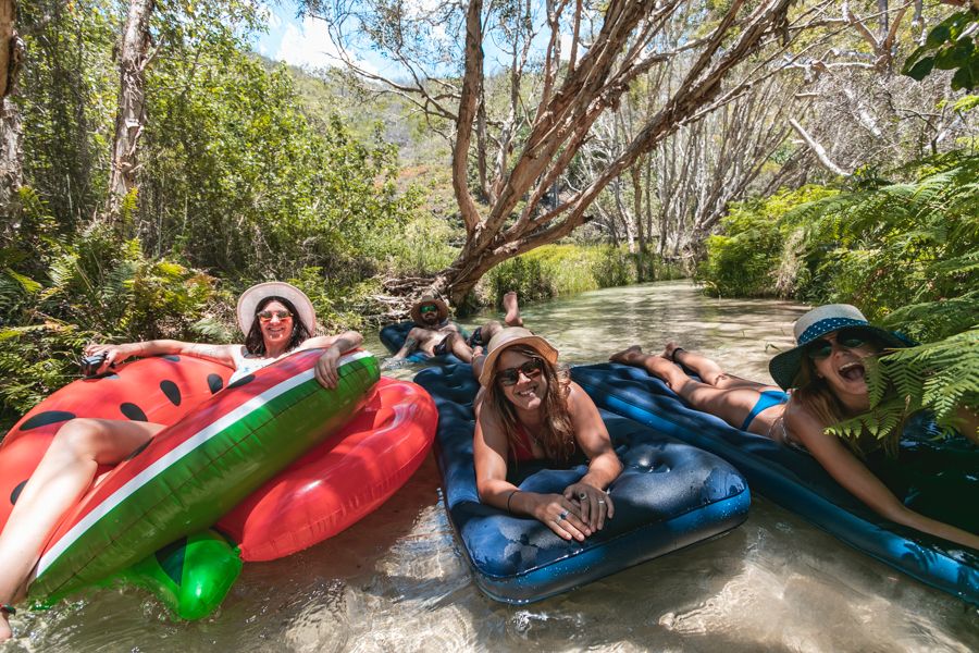 people floating down eli creek on colorful tubes