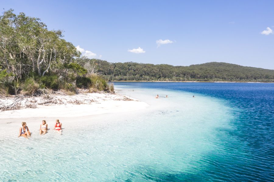 girls sitting on the white sand beach at Lake McKenzie K'gari