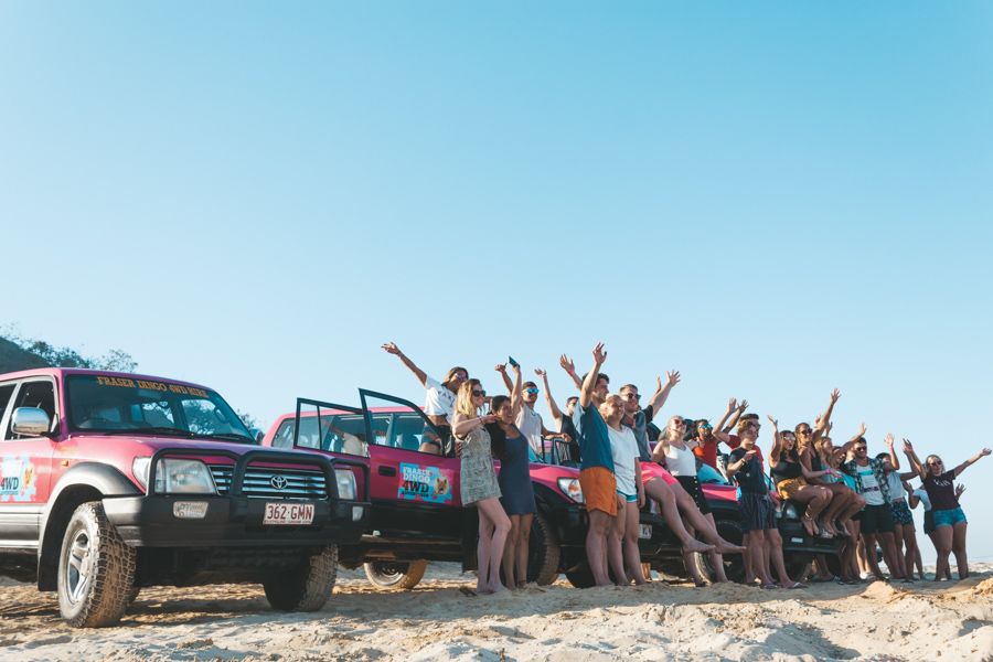 K'gari group tour posing near their 4wds on the beach